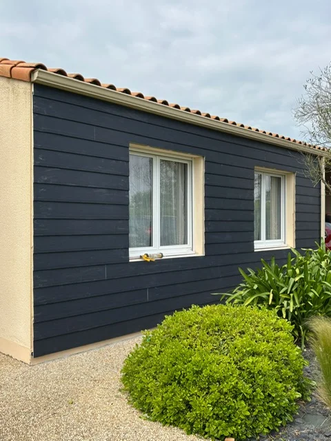 Bardage extérieur en bois sombre sur une maison individuelle, installé par Actiba Menuiseries à Montaigu en Vendée