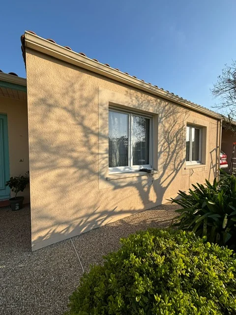 Façade d'une maison de couleur beige, avant l'installation d'un bardage en PVC de couleur gris anthracite.