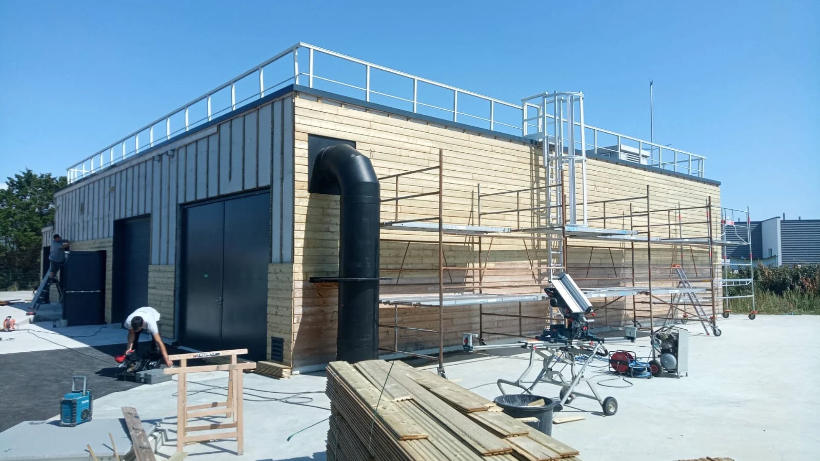 Chantier de bardage en bois  sur un bâtiment industriel en cours de construction par Actiba Menuiseries.