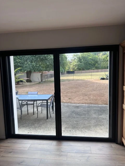 Baie à galandage en aluminium moderne fermée, donnant vue sur la terrasse et le jardin.