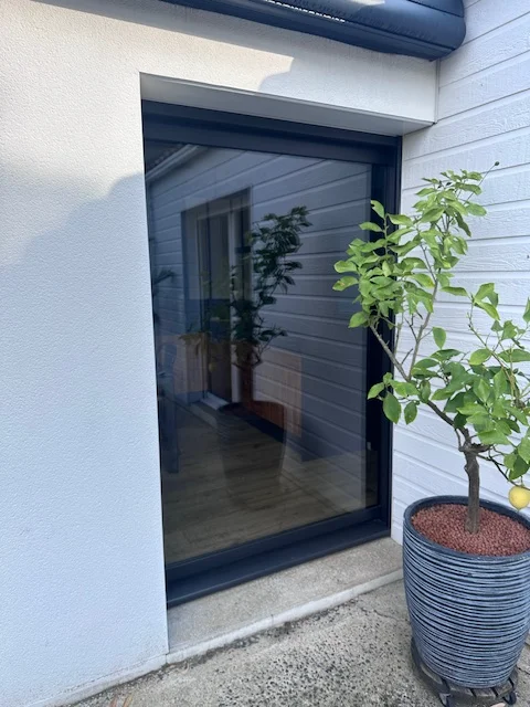 Baie vitrée vue de l'extérieur avec un cadre moderne en aluminium noir. Un rendu esthétique et intemporel.