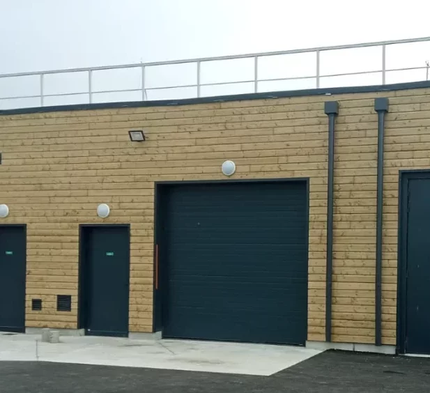 Bâtiment avec bardage extérieur bois et menuiseries extérieures noires modernes pour un rendu élégant.