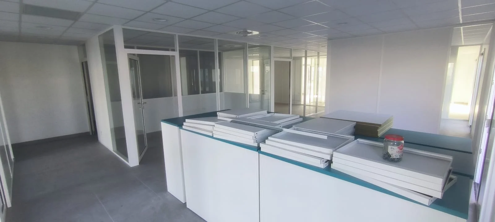 Cloisons modulaires semi vitrées blanches dans des grands bureaux collaboratifs.