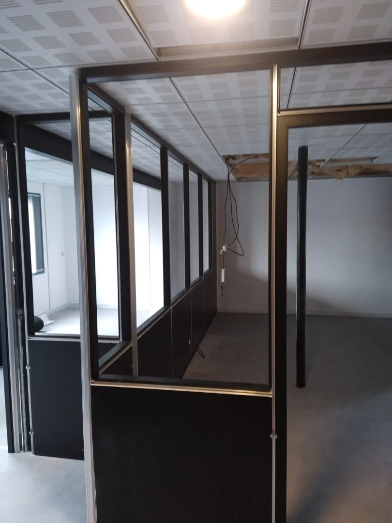 Cloisons modulaires en cours d'installation dans une salle qui réunira plusieurs bureaux individuels.