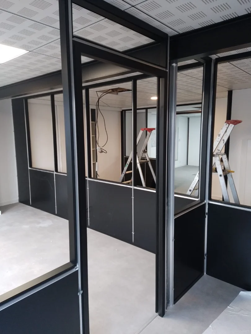 Cloisons modulaires noires semi vitrées en installation dans des locaux administratifs.