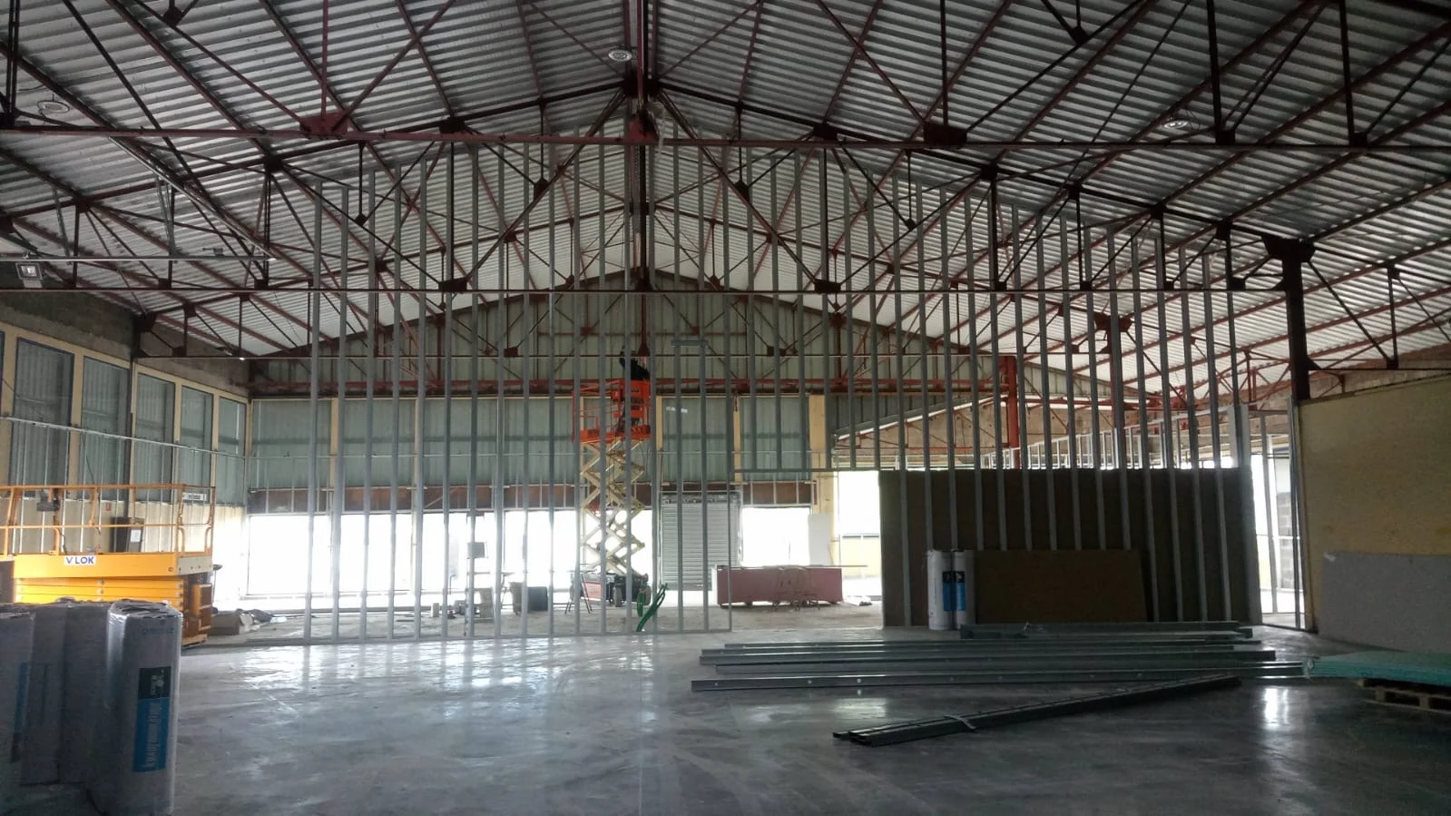 Ossature métallique d'une cloison sèche grande hauteur en construction dans un bâtiment industriel.