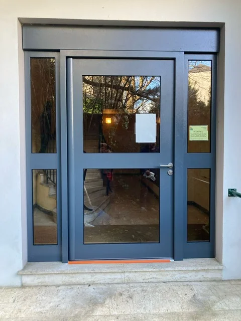 Porte d'entrée moderne d'une résidence urbaine, en verre et métal anthracite. Une porte sécurisée et fonctionnelle