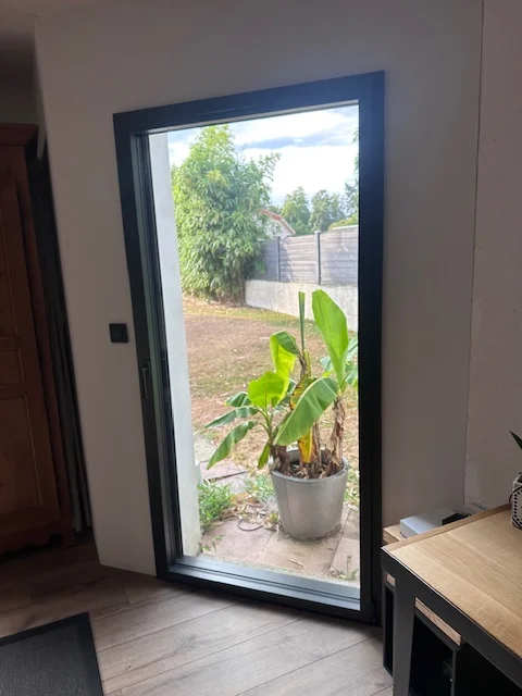 Porte-fenêtre aluminium moderne posée par Actiba Menuiseries ouvrant sur un jardin.